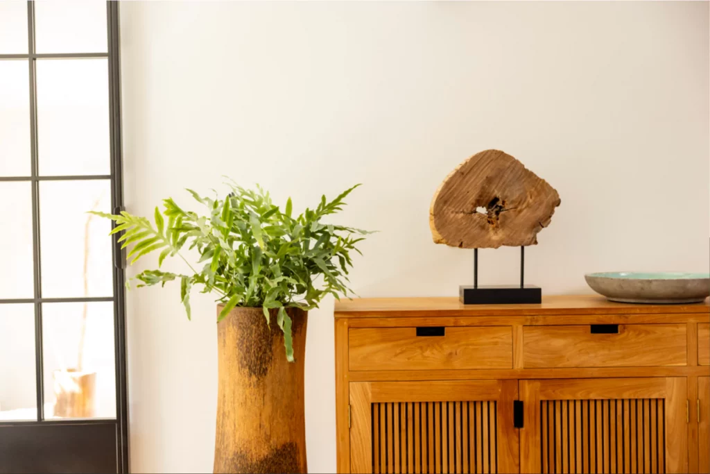 Geräumiges Teakholz-Sideboard als geschlossene Stauraumlösung im Wohnzimmer, mit exklusiver Dekoration und Bodenvase. Diana Engelhard Ordnungscoach.